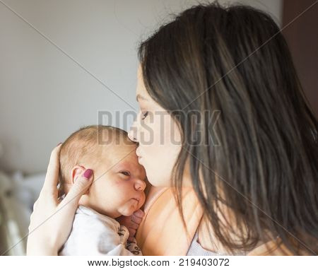 a young mother enjoys the first days of motherhood with her child holding it in her arms