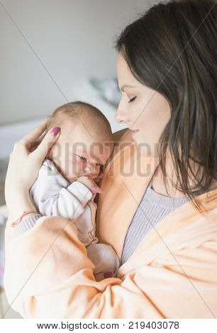 a young mother enjoys the first days of motherhood with her child holding it in her arms