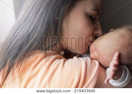 a young mother enjoys the first days of motherhood with her child loving him and holding him in her arms