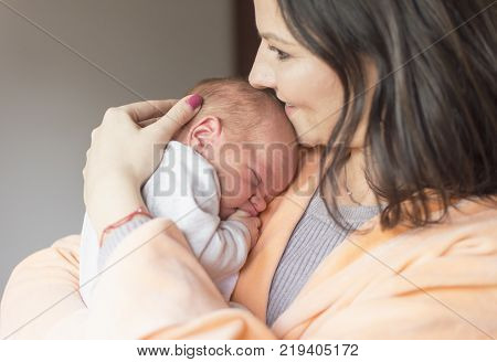 a young mother enjoys the first days of motherhood with her child holding it in her arms
