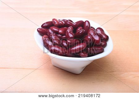 Heap of canned red kidney beans in the sauce in white bowl. vegetarian food. Phaseolus vulgaris
