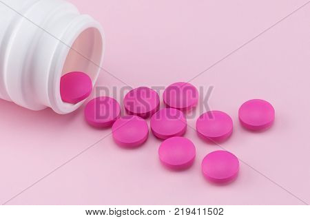pink round pills pouring out of the bottle