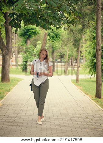Beautiful woman in a business suit in the alley of the city Park. Portrait of a beautiful woman in full length in the Park.