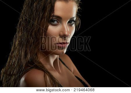 Close up studio shot of a young beautiful female model posing fiercely onblack background looking to the camera copyspace attraction temptation confidence sexuality.
