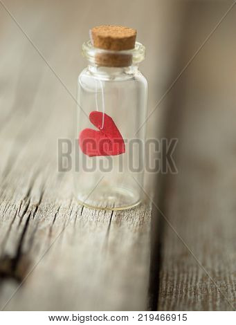 red heart in the glass is closed. on a white rustic wooden table with space for text. Romantic love concept. Valentine's Day greetings card. Valentines theme. Selective focus. Copy space.