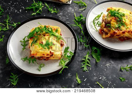 Homemade lasagna with minced beef bolognese and bechamel sauce topped wild arugula, parmesan cheese.