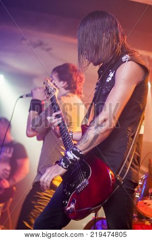 Guitarist playing on stage. Dark background, smoke, spotlights