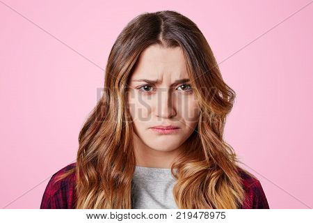Headshot Of Unhappy Sorrorful Female Curves Lips, Looks Desperately At Camera, Being Upset To Hear B