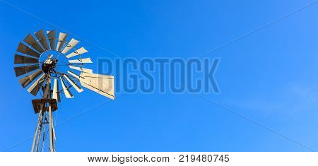 Multi-bladed windpump on blue sky background. Text for space