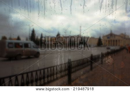 Autumn street on a rainy day view through wet glass