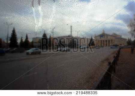 Autumn street on a rainy day view through wet glass