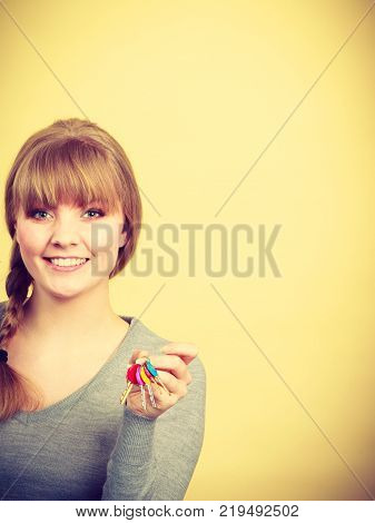 Ownership and property concept. Young blonde smiling female owner with bunch of colorful keys. Woman with key antry to her first own flat.