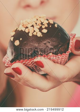 Diet sweets food concept. Woman holding delicious chocolate cupcake with peanut frosting about to take bite