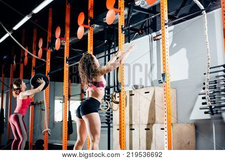 fitness, sport and exercising concept - two woman with medicine balls training in gym
