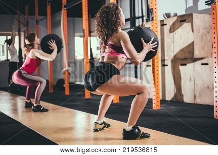 fitness, sport and exercising concept - two woman with medicine balls training in gym