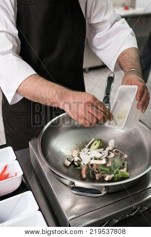 chef works at restaurant kitchen. male cook is preparing a meal in the frying pan. Successful professional lifestyle