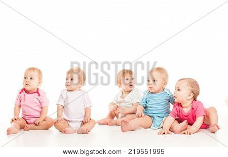 Group of witty babies sitting in different clothes, isolated on white background