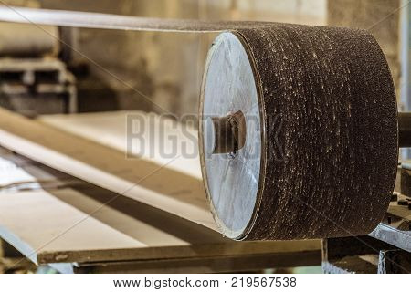 Industrial professional abrasive sanding machine with grinding belt close-up. Mechanized woodworking carpenter tool in carpentry workshop. Selective focus.