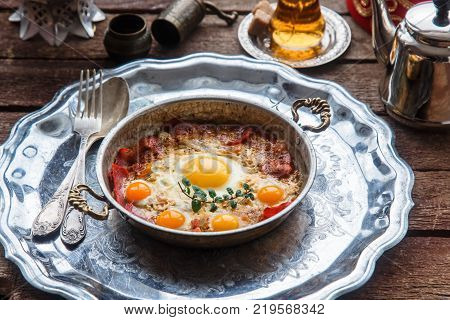 Traditional turkish breakfast with eggs and pastirma, with tea and metal dishware.