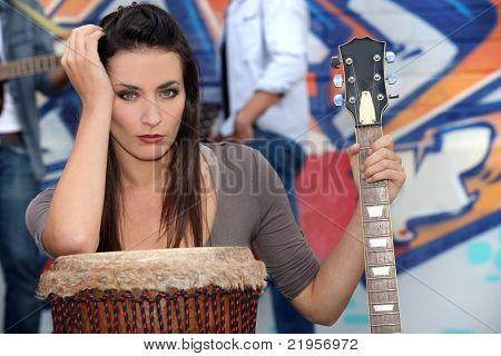 Hudebník se opíral o buben a drží kytara