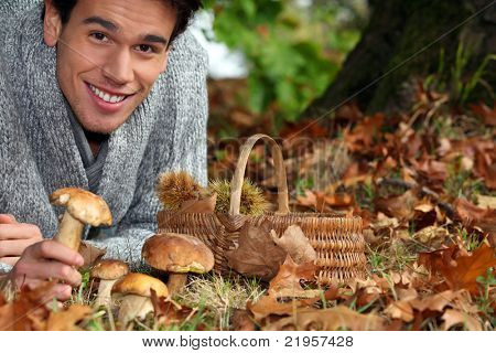 Homme, cueillette des champignons et des châtaignes dans la forêt