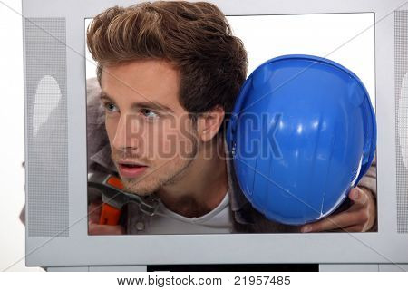Uomo con un cappello duro e martello all'interno di un televisore