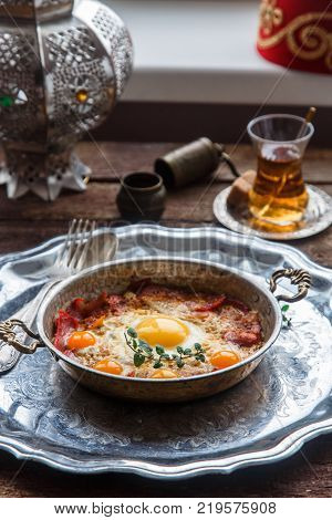 Copper pan with fried eggs and sausages, turkish style.