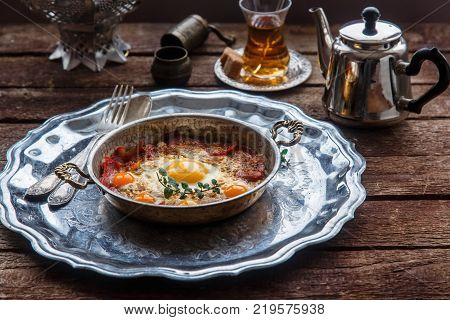 Copper pan with fried eggs and sausages, turkish style.