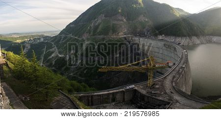 The Inguri hydroelectric power station at sunset is illuminated by the rays of the sun. panorama