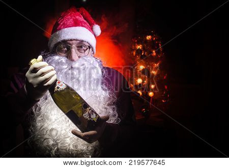Santa Claus toasting with a glass of champagne (Bottle) Santa Claus with a glass of champagne celebrating and smiling. Selective focus dark toned background