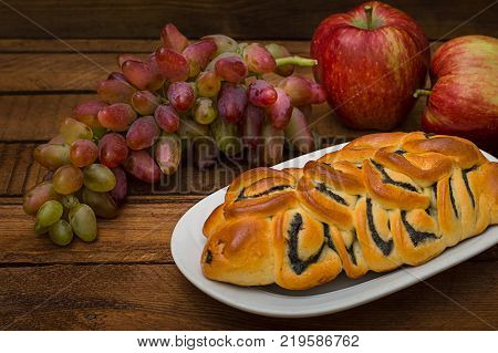 Still life of homemade pastries, sweet poppy pie on the background of fresh fruits, apples and grapes. Top View. Wooden rustic background