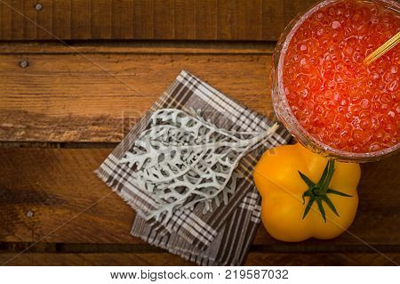 Red caviar in glass jar with gold spoon close up. Sea food. Healthy eating. Diet. Wooden rustic background. Top view. Selective focus