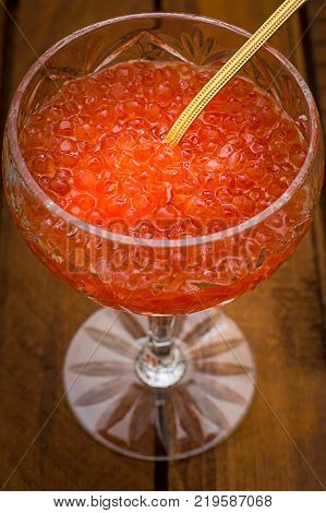 Red caviar in glass jar with gold spoon close up. Sea food. Healthy eating. Diet. Wooden rustic background. Top view. Selective focus