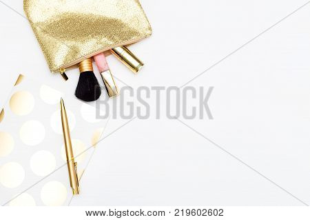 Cosmetics for make-up and notebook with pen in gold color on a white background. Copy space
