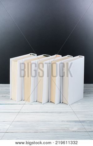 Open black and Whitel books on wooden table, black board background. Back to school. Education business concept
