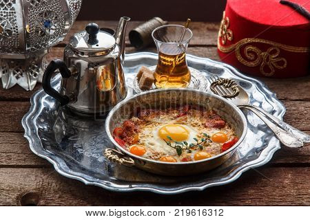 Fried egg with cured meat, traditional turkish breakfast, served in metal dishware, rustic.