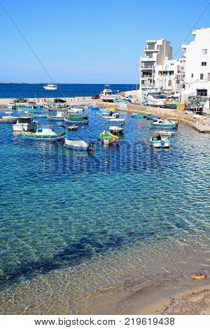 SAN PAWL, MALTA - APRIL 2, 2017 - Traditional Maltese Dghajsa fishing boats moored in the harbour with town buildings to the rear San Pawl Malta Europe, Arpil 2, 2017.
