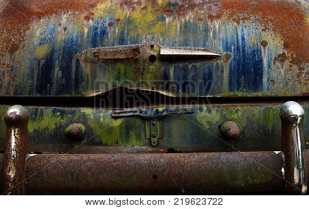 Old junk car rusted trunk with colorful peeling paint and chrome bumper on Route 66