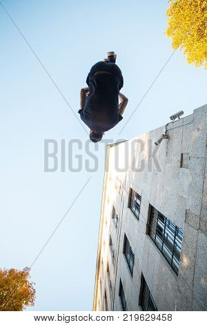 Young man doing a side flip or somersault while practicing parkour on the street.