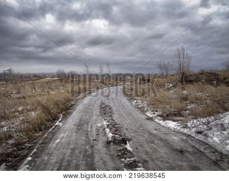 Winter steppe in december. Grunge landscape. Dramatic sky. Thaw. Ice road