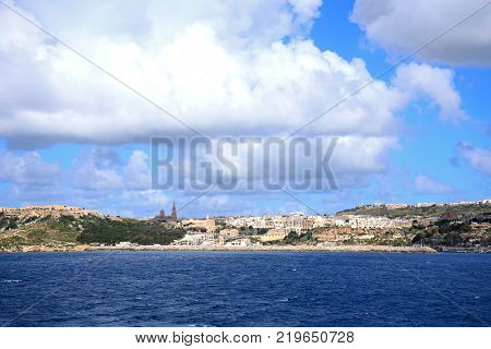 View of the town and harbour with the Ghajnsielem Parish Church and Our Lady of Loudes Church on the hillside Mgarr Gozo Malta Europe.