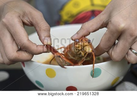 Hands holding cooked shrimp on Noodle soup (Tom Yum). It's difficult for some people to remove shell to eat shrimp.