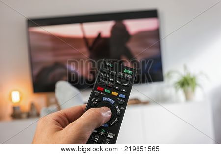 POV-Shot from feeds and a hand holding a TV Remote control to ZAP on tv at home. ideal for websites and magazines layouts