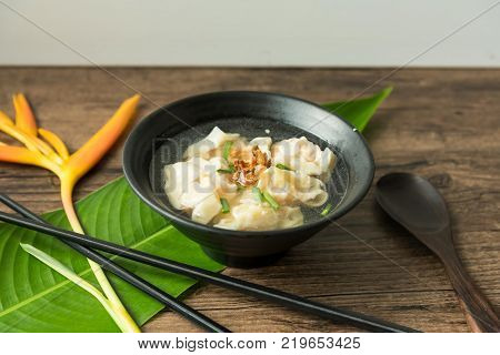 Shrimp wonton with braised pork in soup on wooden table - Asian food style 