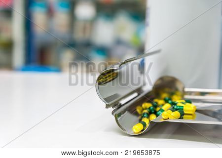Many green and yellow pill capsules  are placed on the counting tray.