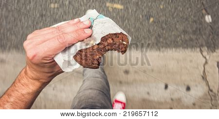 Male hand holding a bitten Chocolate Cookie at the streets. ideal for websites and magazines layouts