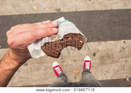 Male hand holding a bitten Chocolate Cookie at the streets in paris. ideal for websites and magazines layouts