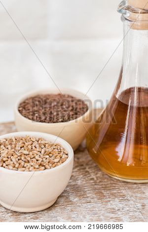 Close up wooden bowl with wheat grains and seed oil in decanter organic food concept