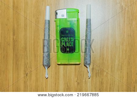 Amsterdam, Netherlands - December 14, 2017: The lighter and Pre-rolled marijuana joint on wooden background at Amsterdam, Netherlands on December 14, 2017