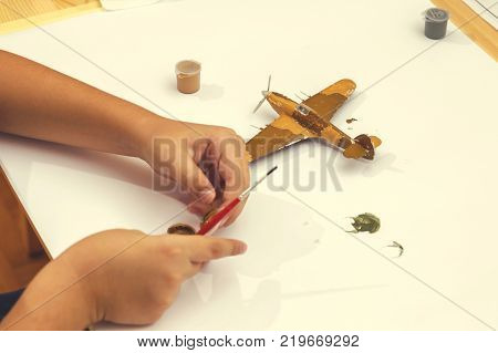 Painting plastic model kit of ww2 aircraft plane at home. Boy hobby and leisure. Vintage style.